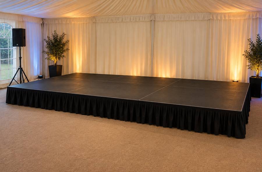 Modular stage with black skirting set up inside a marquee